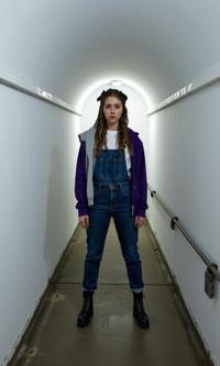 fashion photography,of a woman as a death metal front figure with dreadlocks wearing studded ankle boots ,dressed in grey cardigan,white shirt