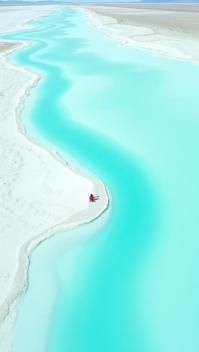 teal theme, A surreal, bird s eye view of the Salinas Grandes Great Salt Flats in the Patagonian Desert, showcasing the geometric patterns and vivid white hues of the salt deposits contrasting with the deep blues of the water and the muted tones of the surrounding desert Include a few tiny