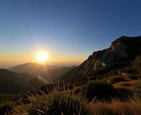 photograph, lush mountains and Solar eclipse in background, masterpiece, angle from below of a It s a hard knock life